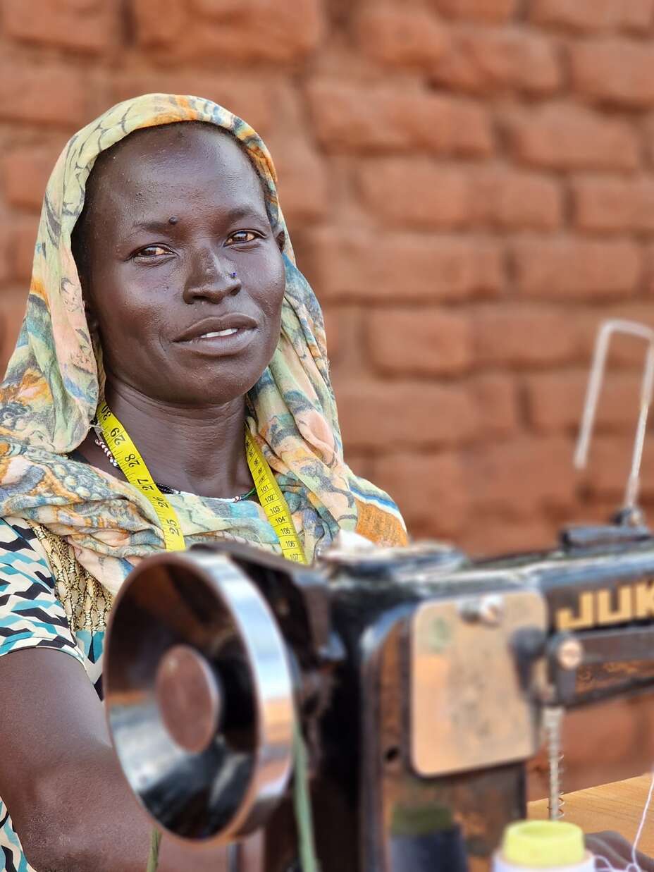 Rihab, eine sudanesische Geflüchtete in Südsudan, erhielt durch das IRC-Projekt eine Nähmaschine und Schneidertraining, um sich selbst zu versorgen.